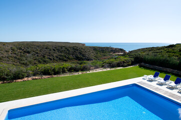 High angle view of a swimming pool in the garden of a holiday villa with views across scrubland to the sea