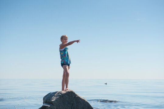 Young Girl Standing on Rock by Ocean