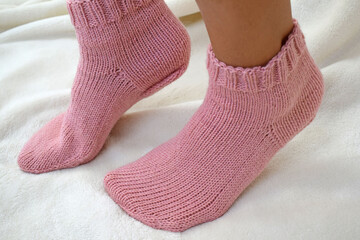 Pink wool socks tied with knitting needles.