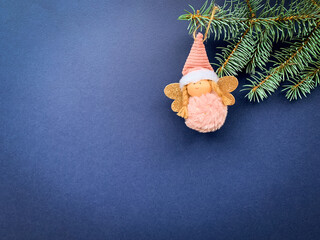 Cute toy angel with hanging on a Christmas tree over blue background