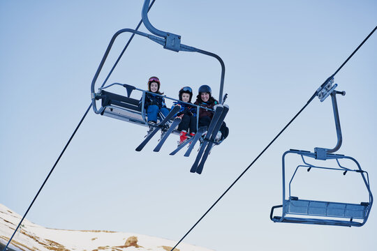 Skiers on a chairlift looking down with a blue background