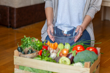 Woman and wooden crate full of fresh vegetables