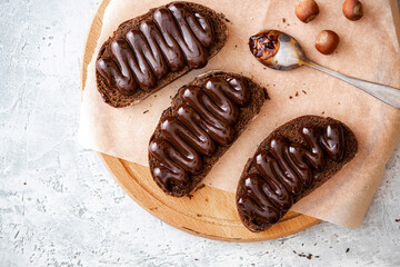 Toast made from rye bread and chocolate on a cutting board top view. Tasty sweet breakfast.
