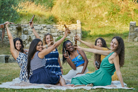 Group of women friends drinking beer in a park on summer day