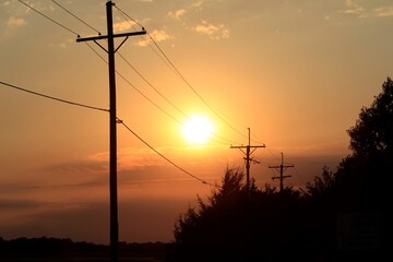 Power line silhouette's at Sunset with tree's and clouds north of Hutchinson Kansas USA out in the country.