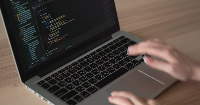A young woman writes code on a modern laptop
