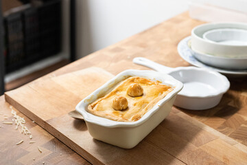 Tart or savory pie in a white dish at wooden table