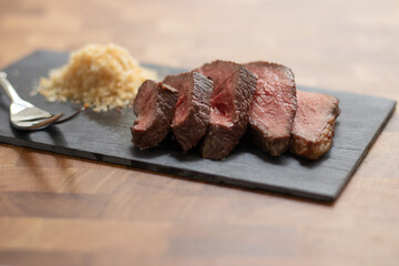 Picanha meat, Brazilian cow steak, served with farofa at a wooden table