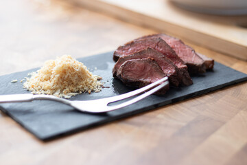 Picanha meat, Brazilian cow steak, served with farofa at a wooden table