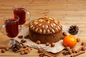 Obraz na płótnie Canvas Homemade cake with almonds and two glasses with mulled wine on a wooden table