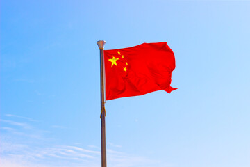 National flag of China or officially the People's Republic of China (PRC) waving in the wind on blue sky background. 