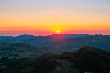 Obraz premium Red sun rising over the colorful sky and mountains landscape. Sunrise in mountains, Natural background. Italian Apennine 
