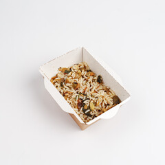 wild rice with spices, nuts and mushrooms in a cardboard plate. Food delivery