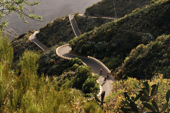 Pulled back view of cyclist group on winding road in Masca, Tenerife