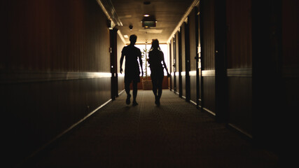 Back view of Caucasian young couple walking hotel hallway