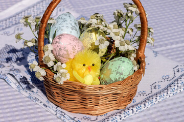 A wicker basket with decorative Easter eggs and fresh flowers is on the table.