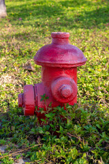 Vintage red fire tube at green grass in Sanya city on a sunny day. City fire extinguishing system...