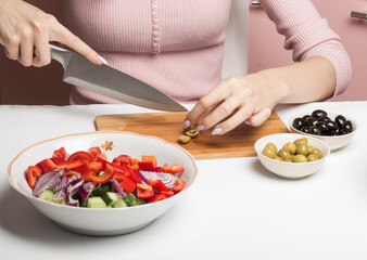 she cut the olives on a cutting Board for a salad