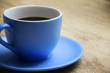 Coffee time with large blue cup with black coffee on wooden table. 