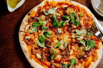 Mushroom pizza with addition mozzarella cheese and herbs on a wooden table, top view