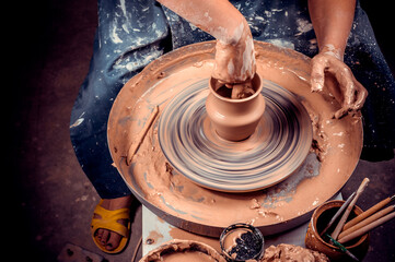 hands of potter do a clay pot