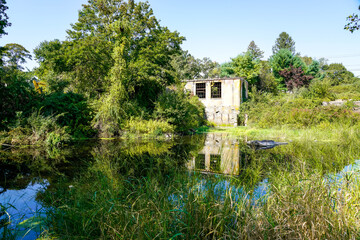 Abandoned mill reflects on pond in Shannock, Rhode Island. 