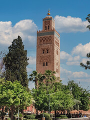 Fototapeta na wymiar view of the famous tower Kutubiyya Mosque in Marrakesh. Garden in the foreground. Local people are walking around and so are the tourists.