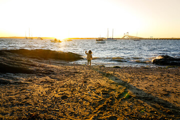 Little girl plays on beach at sunset in Newport, Rhode Island.