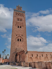 Fototapeta na wymiar view of the famous tower Kutubiyya Mosque in Marrakesh with a clear sky and people sitting next to the building