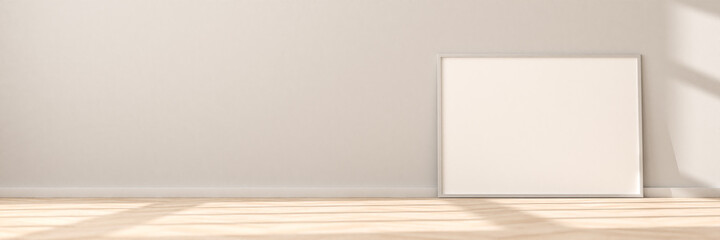 Horizontal empty Picture Frame on parquet floor leaning against bright wall. Sunlight flooding in...