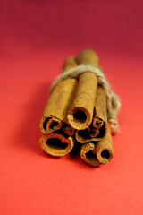 five brown cinnamon sticks tied with thread on a red background on the side . Christmas symbols and baking spice