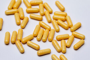 Yellow capsules with medicine are scattered on a white background.
