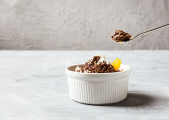 Chocolate mousse garnished with a tangerine wedge and white chocolate shavings in white bowl and...