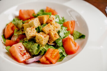 Caesar salad with croutons, quail eggs, cherry tomatoes and grilled chicken in wooden table
