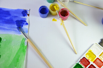 gouache paint brushes and children's drawings. photo child paints a brush with watercolor honey...