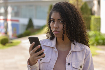 Fototapeta na wymiar Black woman on urban background texting on cellphone