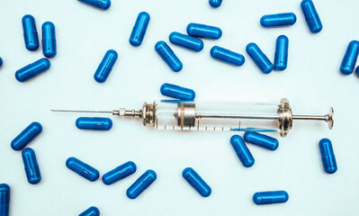 Old glass syringe and blue pills
