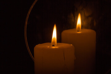 Brennende Kerze mit Spiegelung rechts.