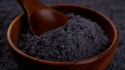 blue butterfly pea powder in wooden bowl close up. superfoods