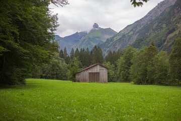 Fototapeta na wymiar Eine Scheune auf einer Wiese vor den Bergen in Bayern