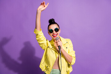 Photo of crazy cool lady sing song mic raise hand wear youngster clothes isolated over violet color...