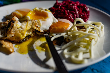 Fried eggs with mushrooms, long cheese noodles and beetroot caviar, a hearty fried dish for Breakfast with appetizers. The flowing liquid yellow egg yolk