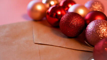 Envelope from craft paper with christmas red and pink balls on pink festive background