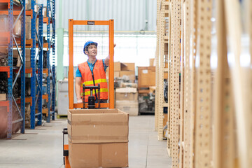 Asian male warehouse worker in safety vest and helmet driving and operating on forklift truck in...