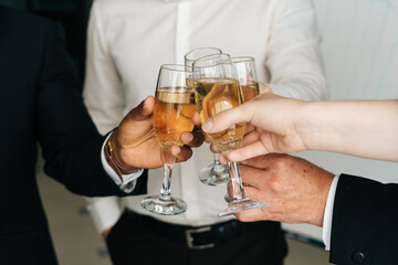 Close-up view of business team of multinational employees holding clinking glasses of champagne and smiling cheerfully at corporate New Year or Happy Christmas eve.