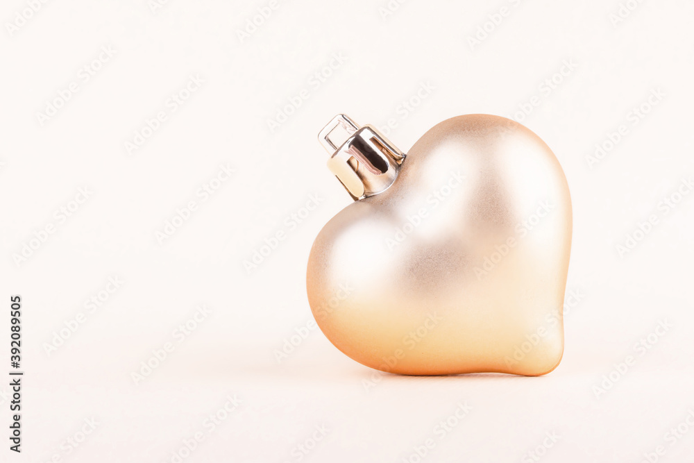 Wall mural christmas tree toy in the shape of a heart golden color on a light background with copy space. close