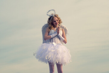 Fototapeta na wymiar Angel child girl with curly blonde hair - Innocent girl concept. Charming curly little girl in white dress and wings - angel cupid girl. Real fairy from magical stories.