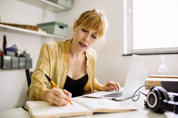 Woman working from home taking notes in note book