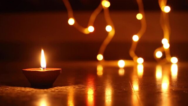 Woman's hand lighting decorative Diyas, Lighting Diya and walking, Happy Diwali, Closeup shot of the Diya, Loop background Diya