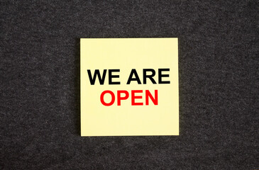 Yellow sticker on the dark gray texture background with text We are Open